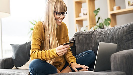 Kvinna håller i mobil och tittar på dator