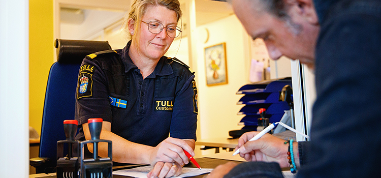 Tulltjänsteperson och kund fyller i papper vid tullklarering