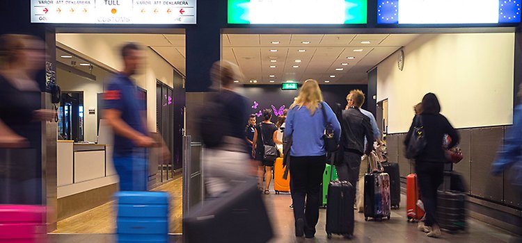 Personer med resväskor passerar tullen vid gränsen.